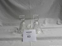 Pair of clear crystal candle holders displayed side by side with a MaxSold lot card in front.
