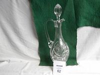 Full front view of the crystal claret jug against green background showing cut pattern and handle.
