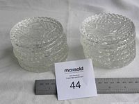 Set of twelve round clear crystal coasters stacked in two piles of six each, shown with a ruler for scale.
