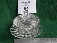 Photo showing the lidded crystal dish on a green background with a ruler for scale, indicating size approximately 9 cm diameter.
