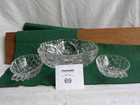 Front view of two small crystal side dishes placed on either side of larger crystal serving bowl showing diamond and leaf cut patterns.