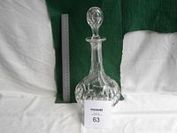 Front view of heavy crystal decanter placed beside a ruler showing approximately 30 cm height, clear cut-glass design visible.