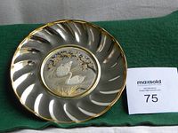 Front view of silver-tone round wedding dish with scalloped edge and central embossed swans under a floral arch, gold trim on rim and gold highlights on design.