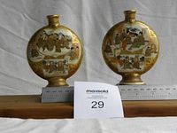 Wide front view of both vases on a wooden base with ruler showing scale