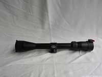 Side view of black Simmons rifle scope with lens covers present on both ends, positioned horizontally.