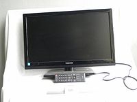 Front view of Toshiba 24-inch flat screen TV with universal remote and power cord visible