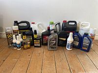 Full view of all automotive fluid containers arranged in one group on the floor against a wall.