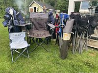 Photo showing a group of foldable camping chairs including blue, gray with Roots branding, maroon, and black chairs along with carrying bags.