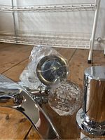 Photo showing the faucet with clear crystal knobs and part of the faucet body with attached drain plug.