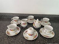 Photo shows full tea set with 4 cups, 4 saucers, creamer, and sugar bowl with lid arranged on countertop.