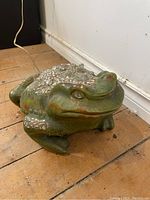 Side/front angle of ceramic frog lamp showing textured silver accents and electrical cord