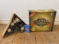 Poker chips in multiple colors in a divided wooden tray, two decks of cards in tuck boxes, and the boxed TV Poker game system seen from an angle