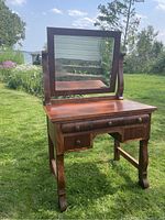 Front view of vintage solid wood vanity table with swing mirror and four wooden knob drawers.