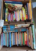 Two boxes filled with various children's books including Disney, Treasure Island, and other titles.