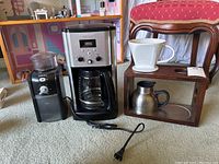 Full lot arranged side by side on carpet showing coffee maker, grinder, and Starbucks drip coffee set with wooden stand, ceramic dripper, and stainless steel carafe.