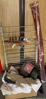 Metal drying rack with hangers, brass drapery rod in plastic covering, assorted linens including crocheted pieces and a green planter