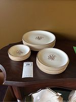 Three stacks of plates and bowls on a wooden surface showing a floral design in the center, cream background with brown decoration.