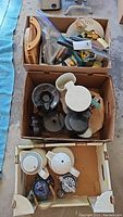Overview of three boxes containing assorted kitchen items including carafes, teapots, kitchen cutters, and gadgets.