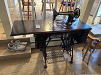 Side view of vintage Singer sewing machine mounted in the table with treadle base and multiple drawers.