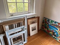 Corner corner shot of multiple empty frames stacked against wall with framed art
