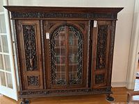 Full frontal view of three-piece carved oak bookcase with central stained glass doors