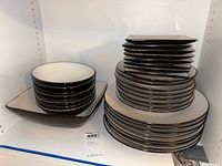 Photo showing stacked square and round plates all featuring white texture radiating pattern with dark rims.