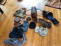 Overview of all purses and bags on wooden floor showing a variety of shapes, sizes, colors and materials including beaded and woven styles.