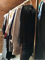 Photo of several women's coats and jackets hanging on a rack featuring different materials including leather and textured fabrics.