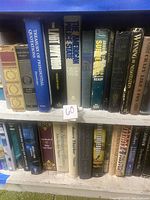 Two shelves of hardcover books with visible titles representing various genres including history, politics, fiction, and fantasy. Books appear in very good condition.