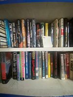 Two shelves of hardcover books with titles visible from vintage and contemporary authors across various genres.