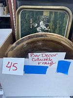 Photo of bar decor and collectible trays including Captain Morgan mirrored tray and an aluminum tray behind it.