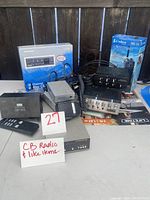 Overview showing multiple CB radio units, boxed handheld radio, power modules, microphones and cables