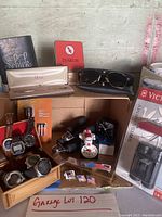 Overview of assorted watches, tools, pen, shaver, sunglasses, binoculars and small accessories arranged on table