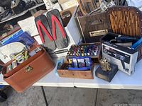 Overview of the entire assortment on a table showing sewing kits, Japanese sandals, thread spools, boxed items, and collectibles