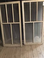 Two antique wooden window frames with multiple glass panes, worn paint and visible signs of age.
