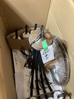 Ceiling light chandelier unassembled in box showing metal arms, central wooden components, wiring and mounting hardware.