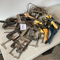 Wide shot of clamps showing variety of metal and plastic clamps placed on a white surface, labeled with lot number.