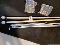 Full set of wood curtain rods with finials, mounting brackets and hardware laid on a black surface.