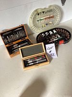 Photo showing all three sets in the lot including wooden box with blades, orange case, and plastic cases with Dremel attachments