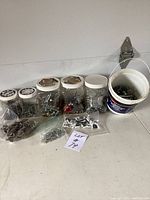Full lot view showing multiple jars, plastic bags, and a bucket with assorted screws and hardware pieces