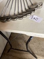 Ten right-handed Maxfli irons laid out on a table, showing club heads and shafts, all in lightly used condition.