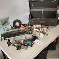 Wide view showing various tools on a white table, highlighting the Craftsman dovetail template, clamps, a handheld tool, and a bulb socket.
