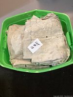 Photo of well-used painting tarps with paint marks folded inside a green bin.