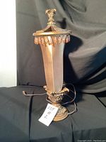 Full view of the bronze-tone table lamp with fabric shade and decorative top finial.