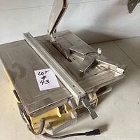 Front angled view of tile saw showing metal table surface and blade with guard.