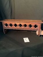 Front view showing entire wood shelf with decorative quatrefoil pattern and carved trim