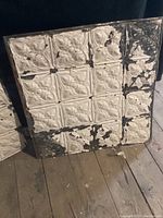 Single sheet of 4×4 embossed tiles showing white paint finish and areas of chipping