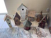 Overview of all seven bird houses arranged on floor showing size and design variation