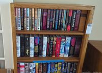 Photo showing a bookshelf with hardcover books featuring multiple Stephen King books and a John Adams book.