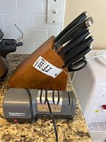 Full view of butcher block knife holder with knives and Chef's Choice electric sharpener on countertop.